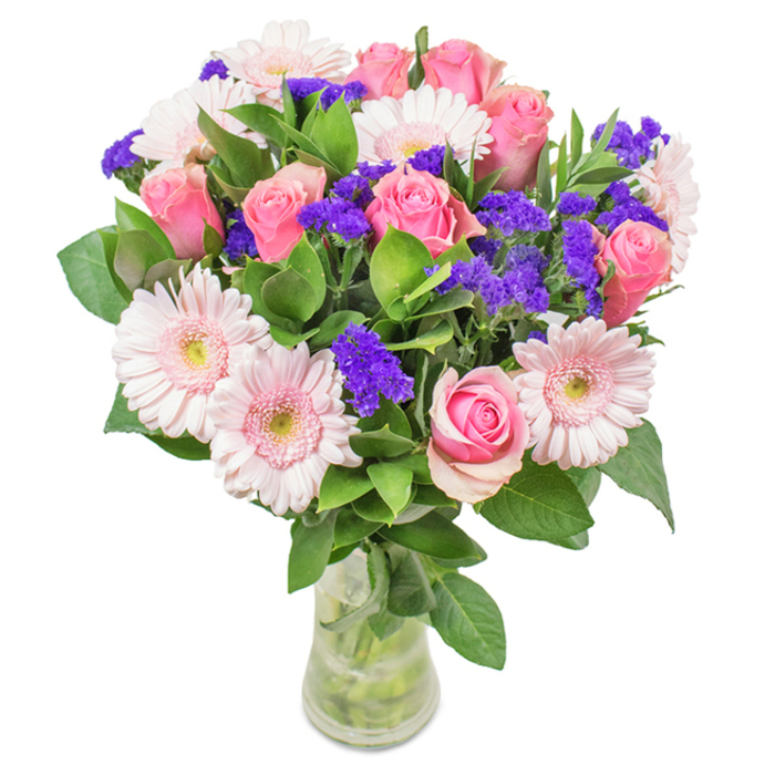 Expertly arranged in a pristine, clear glass vase and set against a bright backdrop, this enchanting bouquet from Tottenham features a delightful medley of blossoms. At its core, you'll find seven to nine lush pink roses, some tightly furled with petals in classic natural spirals, and others thoughtfully beginning to open, catching and reflecting daylight in soft hues. Complemented by five to seven pale pink gerbera daisies, each bloom radiates outward with large, rounded petals and light centres that almost glow ivory. Clusters of vivid purple statice weave between the more prominent flowers, lending bold splashes of colour and a slightly papery texture. The bouquet is anchored with an abundance of deep green foliage and natural stems, visible through the water in the vase, reminiscent of the parks and community gardens that dot Tottenham. The entire arrangement is characterized by freshness, vibrancy, and a sense of refined artistry - ideal for celebrating birthdays, anniversaries, or simply as a bright note sent across Tottenham with same-day flower delivery. Every element is selected for impact and balance, creating a bouquet that delivers joy, warmth, and a reminder of the area's welcoming spirit.