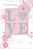 This anniversary card radiates the feeling of enduring romance, as if it has been chosen with care after a stroll past the flower stalls that brighten Tottenham's side roads. The central focus is the word 'LOVE,' formed in soft, raised glitter that looks almost velvety to the touch. Each letter is a gentle blush pink edged in silver, and the 'O' is transformed into a shimmering heart, textured in brighter silver glitter that catches the light like a polished charm. The letters rest on a subtle blush panel that glows against a pale, pearly background, giving the impression of layers and depth. Around this heart-shaped focal point, delicate blossoms in blush, mauve, and soft white appear to unfurl with a watercolour softness, their edges gently blurred as though painted with a fine, damp brush. Slender stems and swirling tendrils weave between the flowers, sketched in fine grey lines that echo the graceful curves of a florist's ribbon. Tiny flourishes-petals in mid-fall, looping swirls, and almost-hidden butterflies-add movement and a whisper of whimsy, reminiscent of an English spring garden tucked away behind terraced houses near Tottenham Green. At the top and inside, the phrases On Our Anniversary and I love you today and always are written in a quiet, graceful script, the letters spaced with a sense of calm confidence. The whole composition feels intimate and meaningful, like a keepsake to treasure alongside a fresh anniversary bouquet delivered to a home in N15 or N17.